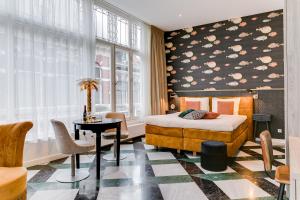 a bedroom with a bed and a table and a window at Brasss Hotel Suites in Haarlem