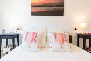 sypialnia z białym łóżkiem z poduszkami i obrazem w obiekcie TGH Málaga we love the sea w Maladze