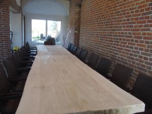 a long wooden table in a room with a brick wall at Anc. Seigneurie de Boucaut in Leuze-en-Hainaut