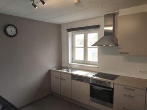 een keuken met een wastafel en een klok aan de muur bij Maneveld in Opglabbeek