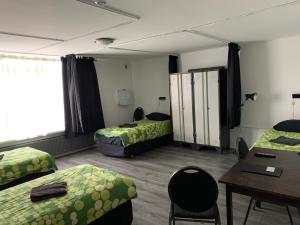 een kamer met 2 bedden, een tafel en een bureau bij Pension Moerdijk in Moerdijk