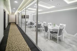 restauracja z białymi stołami, krzesłami i lustrami w obiekcie Kamienica Pod Neptunem w mieście Puck