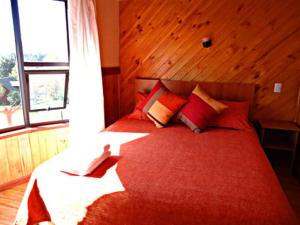a bedroom with a large red bed with a window at Boomerang Inn in Pucón