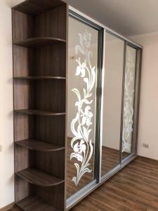 ein Bücherregal aus Holz mit einer Glastür mit Blumenmuster in der Unterkunft Квартира с двумя комнатами в Ж/К Атлант (ул. Антоновича 36Д) in Dnipro