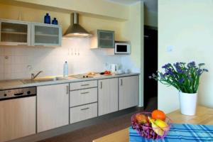 una cucina con armadi bianchi e un cesto di frutta sul tavolo di Villa Baltic - Apartament Chałupy nr 6 a Chałupy