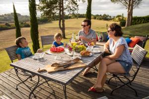 una famiglia seduta a un tavolo da picnic che mangia cibo di La Maison de Maitre a Sainte-Livrade-sur-Lot