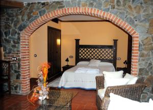1 dormitorio con cama y pared de piedra en Hotel Rural El Rocal, en Ledesma