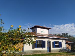 Un petit bâtiment blanc avec une porte bleue dans l'établissement Pousada Ipoema, à Ipoema