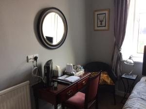 1 dormitorio con escritorio, espejo y cama en Arisaig Guest House en Perth