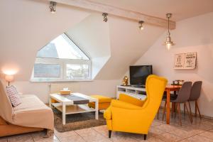 a living room with yellow chairs and a table at Apartamenty Usteckie in Ustka