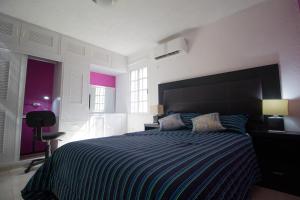 a bedroom with a bed with a blue and white striped bedspread at Casa Zac Nicte Mx-Habitacion IXCHEL in Cancún