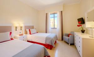 a hotel room with two beds and a television at The Residences at Victoria by Tivoli in Vilamoura