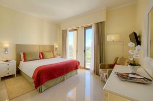 a hotel room with a bed, desk, and dresser at The Residences at Victoria by Tivoli in Vilamoura