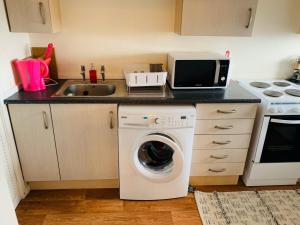 a kitchen with a washing machine and a sink at CyCy Apartment in Aberdeen