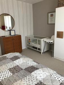 ein Schlafzimmer mit einem Kinderbett, einer Kommode und einem Spiegel in der Unterkunft Feriendomizil Familie Finke in Weener