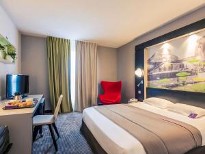 ニオールにあるMercure Niort Marais Poitevinのベッド、デスク、赤い椅子が備わるホテルルームです。