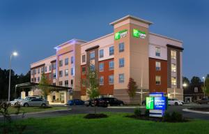 a hotel building with a parking lot in front of it at Holiday Inn Express & Suites - Fayetteville South, an IHG Hotel in Fayetteville