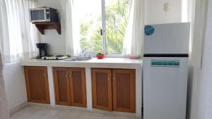a kitchen with a sink and a refrigerator and a window at Villa Lupita in Zihuatanejo