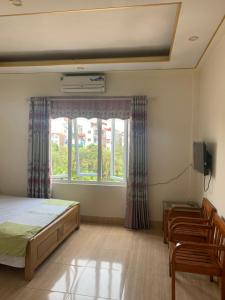 Schlafzimmer mit einem Bett, einem Fenster und Stühlen in der Unterkunft Nhà Nghỉ Diễm Quỳnh in Noi Bai