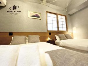 a hotel room with two beds and a window at HOTEL CLA-SS HIROSHIMA-OZU in Hiroshima