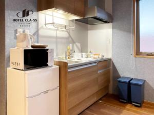 a kitchen with a microwave on top of a refrigerator at HOTEL CLA-SS HIROSHIMA-OZU in Hiroshima