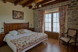 um quarto com uma cama, uma cadeira e uma janela em Apartamentos El llugarón em Miravalles