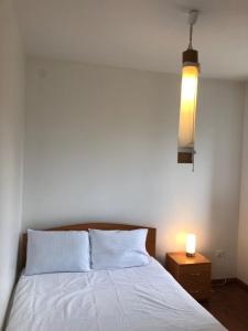 sypialnia z białym łóżkiem i stolikiem nocnym z lampką w obiekcie Apartamentai Palangos centre w Połądze