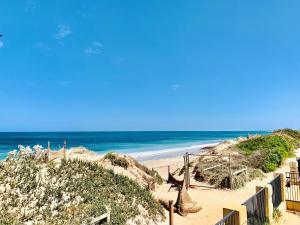 einen Sandstrand mit einem Zaun und dem Meer in der Unterkunft Sunset Beach Holiday Park in Geraldton