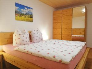 um quarto com uma cama com lençóis brancos e almofadas em Apartment Beim Raffner em Ruhpolding