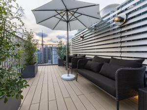 eine Terrasse mit einem Sofa und einem Sonnenschirm auf dem Balkon in der Unterkunft Bay Hotel Tokyo Hamamatsucho in Tokio