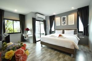 Grand Inter Hotel في Samut Sakhon: غرفة نوم بسرير وتلفزيون وبعض الزهور