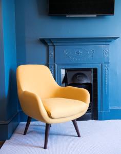 a yellow chair in a blue room with a fireplace at Purchases Restaurant & Accommodation in Chichester