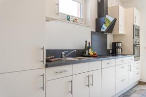 a kitchen with white cabinets and a sink at Neu!!! Ferienhaus-See-Sauna-Kamin-5 Sterne-102m² in Krakow am See