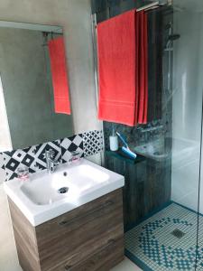y baño con lavabo, ducha y toallas rojas. en Maison d'hôtes MIRADOUR, en Tarnos