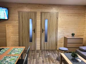 salon z drewnianymi ścianami i drzwiami ze stołem w obiekcie Świerkowy domek w Boszkowie