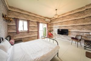 una camera da letto con un muro di mattoni, un letto e una TV di Tony's house a Jiaoxi