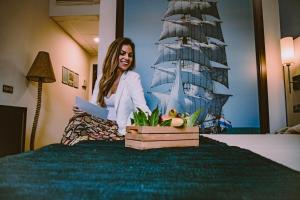 a woman sitting on a bed with a picture of a ship at Hotel Albaida Nature in Mazagón