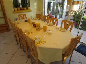 a dining room table with a yellow table cloth and chairs at Locatlantique in Aytré
