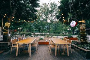 un patio con mesas de madera, sillas y luces en Ancient Street No.5 Youth Chic Hotel en Wuyishan