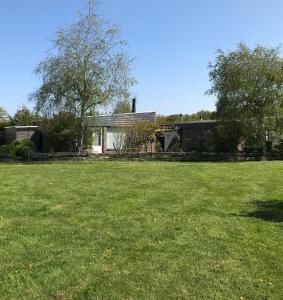 a house in a yard with a green field at Bungalow 221 in Noordwijkerhout