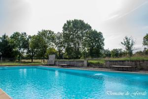 a blue swimming pool with benches and trees in the background at Cosy a la campagne in Solsac