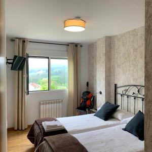 two beds in a bedroom with a window at Pension 23-Vinte e Tres in O Pedrouzo