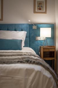 a bed with a blue headboard and a table with a lamp at Gite **** des Bains in Strasbourg