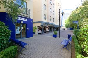 deux bancs bleus sur un trottoir devant un bâtiment dans l'établissement Victoria Lodge Apartments - UCC Summer Beds, à Cork