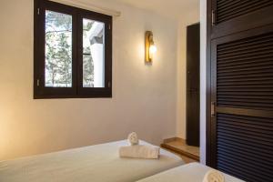1 dormitorio con 1 cama, ventana y toallas en Apartamentos Noray, en Es Caló