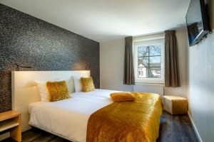 a bedroom with a large white bed with yellow pillows at Aparthotel Ons Epen in Epen