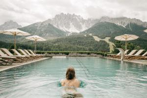 una mujer en una piscina con montañas en el fondo en Naturhotel Leitlhof, en San Candido