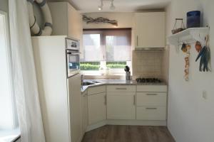 a kitchen with white cabinets and a sink and a window at Vakantiehuis Grevelingen 12 aan Grevelingenmeer. nabij Port Greve in Brouwershaven