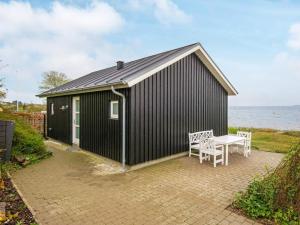 um edifício preto com uma mesa e uma mesa e um banco em One-Bedroom Holiday home in Bjert 1 em Sønder Bjert