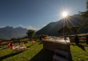 a woman laying in a chair next to a hot tub in the grass at Chalet Saint-Barthélemy Hotel in Nus